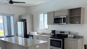 Una cocina moderna con una isla central, electrodomésticos integrados y un ventilador de techo.