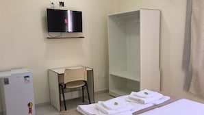 A hotel room with a bed, a desk, a chair, a TV, and a minibar. - Riachuelo Hotel (Resende)