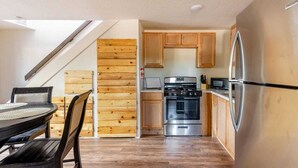 A compact kitchen with wooden cabinets, a stainless steel refrigerator, a stove, and a microwave.