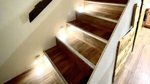 A wooden staircase with built-in lighting, white walls, and a wooden floor.