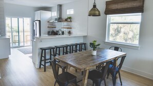 A modern kitchen with white cabinets, a wooden dining table, and black chairs.