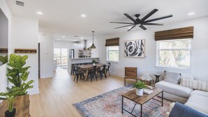 A spacious living area with a dining table, a sofa, and a ceiling fan.