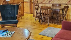 A cozy room with a wooden ceiling, a dining table with chairs, a sofa, and a coffee table. - Toddy's Cabin (Trempealeau)