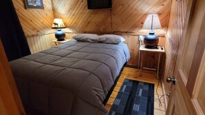 A cozy bedroom with a bed, a ceiling fan, a mounted TV, and two bedside lamps. - Toddy's Cabin (Trempealeau)