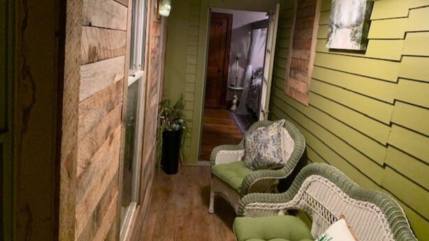 A narrow hallway with wooden walls, a green sofa, and a hanging light fixture. - SWICHBACK TRAIL SUITE AT TRAILS END  B&B (Jim Thorpe)