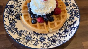 A plate with a waffle, whipped cream, raspberries, and blueberries. - SWICHBACK TRAIL SUITE AT TRAILS END  B&B (Jim Thorpe)
