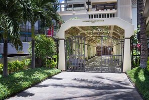 Enter the tropical oasis of Waikiki Beach Tower, surrounded by lush greenery and palm trees.