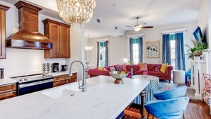Una cocina moderna con una isla grande, armarios de madera y una lámpara de candelabro.