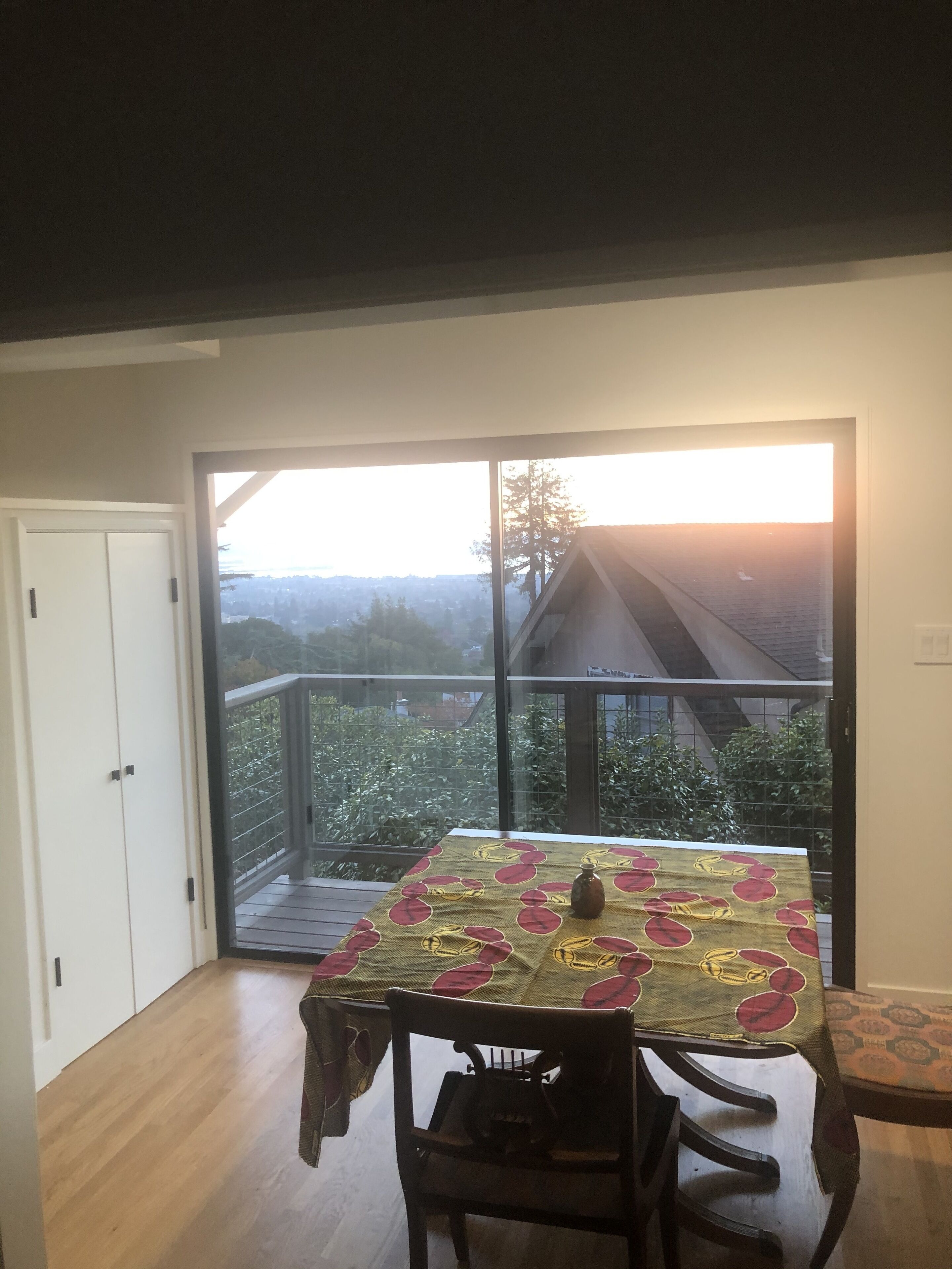 A dining area with a table set for two, a chair, and a view of a cityscape through large windows.
