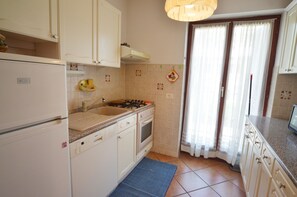 Una cocina con armarios blancos, estufa, fregadero y lavavajillas.
