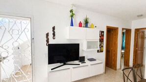 A modern living room with a white entertainment unit, a flat-screen TV, and a dining area with a table and chairs. - Casa Donna" | Holiday Home in Lanzarote - Spain (Playa Honda)