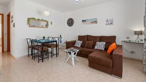 A modern living room with a brown sofa, a dining table with chairs, a round mirror, and a ceiling light fixture. - Casa Donna" | Holiday Home in Lanzarote - Spain (Playa Honda)