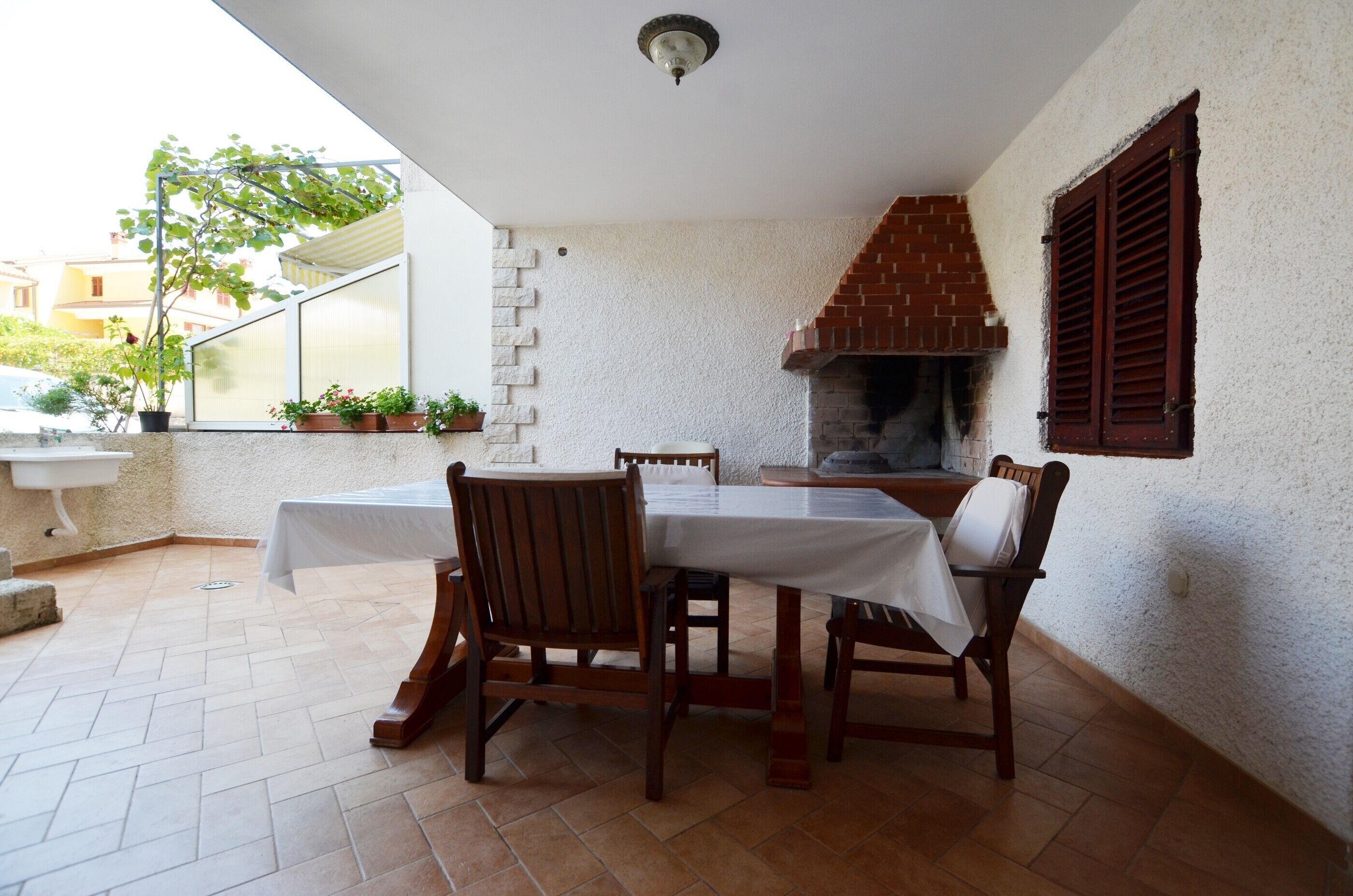 Un patio con una mesa y sillas, una chimenea de ladrillo y plantas en macetas.