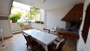 A patio area with a table and chairs, a brick fireplace, and a view of the street. - Jela studio apartment (Rovinj)