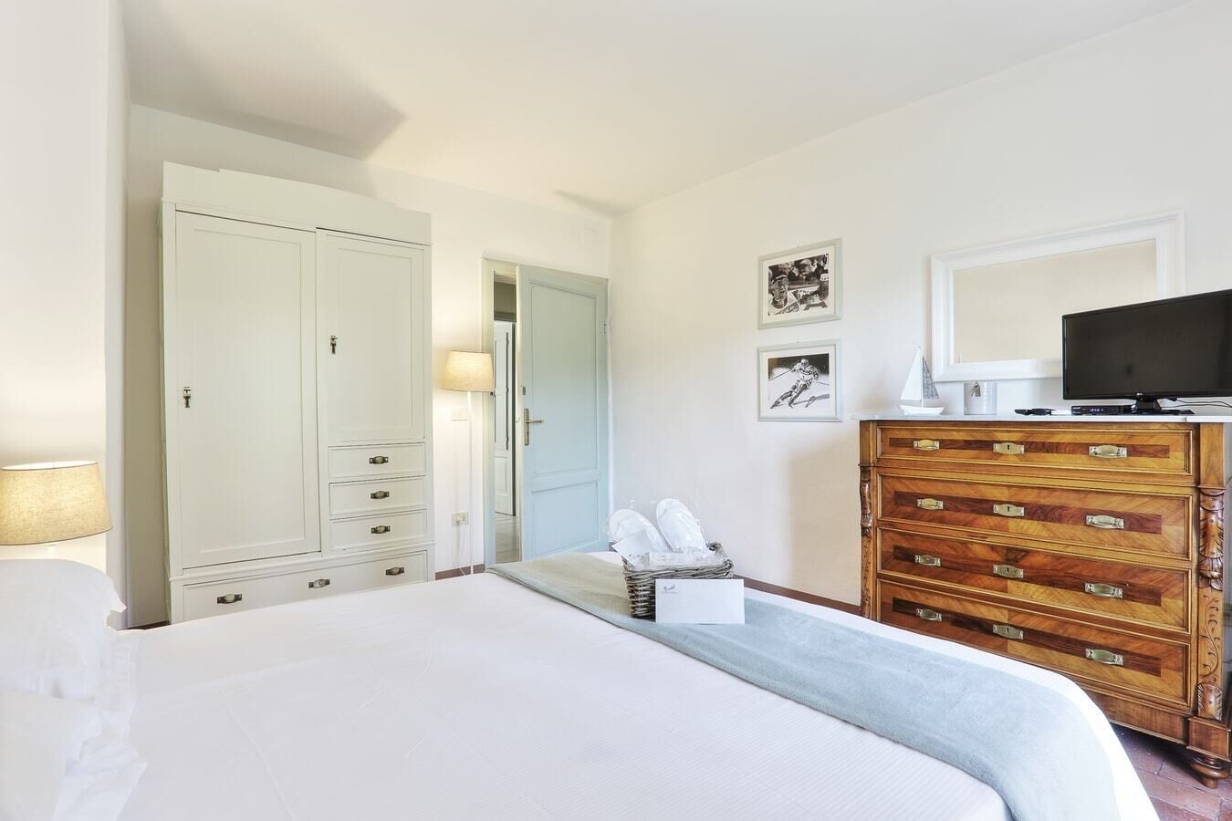 Une chambre d’hôtel avec un grand lit, une armoire, une commode en bois et un téléviseur.