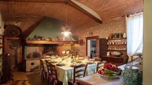 A rustic dining room with a brick ceiling, wooden furniture, and a brick fireplace.