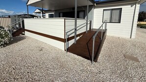 A modern building with a covered outdoor area, a staircase, and a gravel ground.