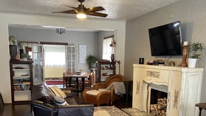 Ett vardagsrum med en soffa, en pall och en tv som är monterad på väggen.