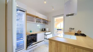 A modern kitchen with a built-in dishwasher, white cabinets, and a wooden countertop.