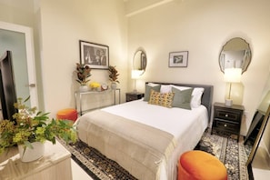 A hotel room with a large bed, bedside tables, a dresser, a mirror, and a potted plant. - Classic DTLA Glamour Loft w/ Rooftop Pool, 360° Views + Parking (Los Angeles)