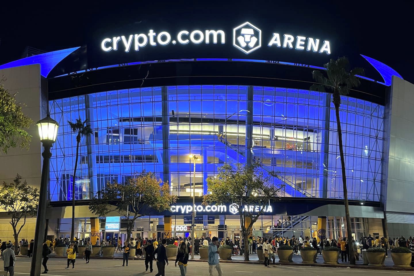 Un edificio grande y moderno con un llamativo letrero de Crypto.com Arena, con fachada de vidrio y entrada curva.