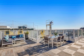 Eine Dachterrasse mit Holzdeck, Sitzgelegenheiten im Freien und freiem Blick auf die Stadtlandschaft.