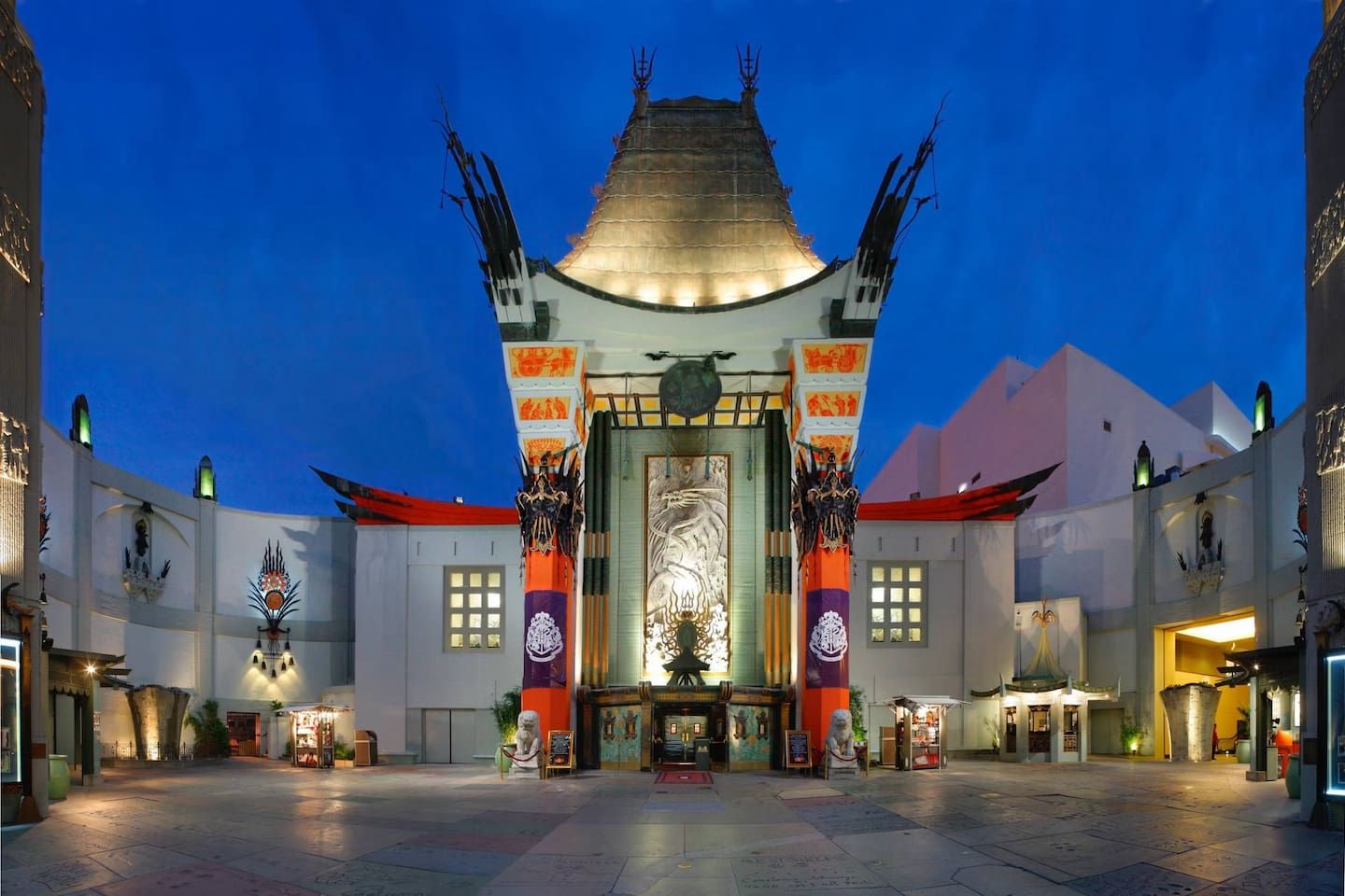 A traditional building with a central entrance, flanked by two pillars with intricate designs, and a tiled courtyard.