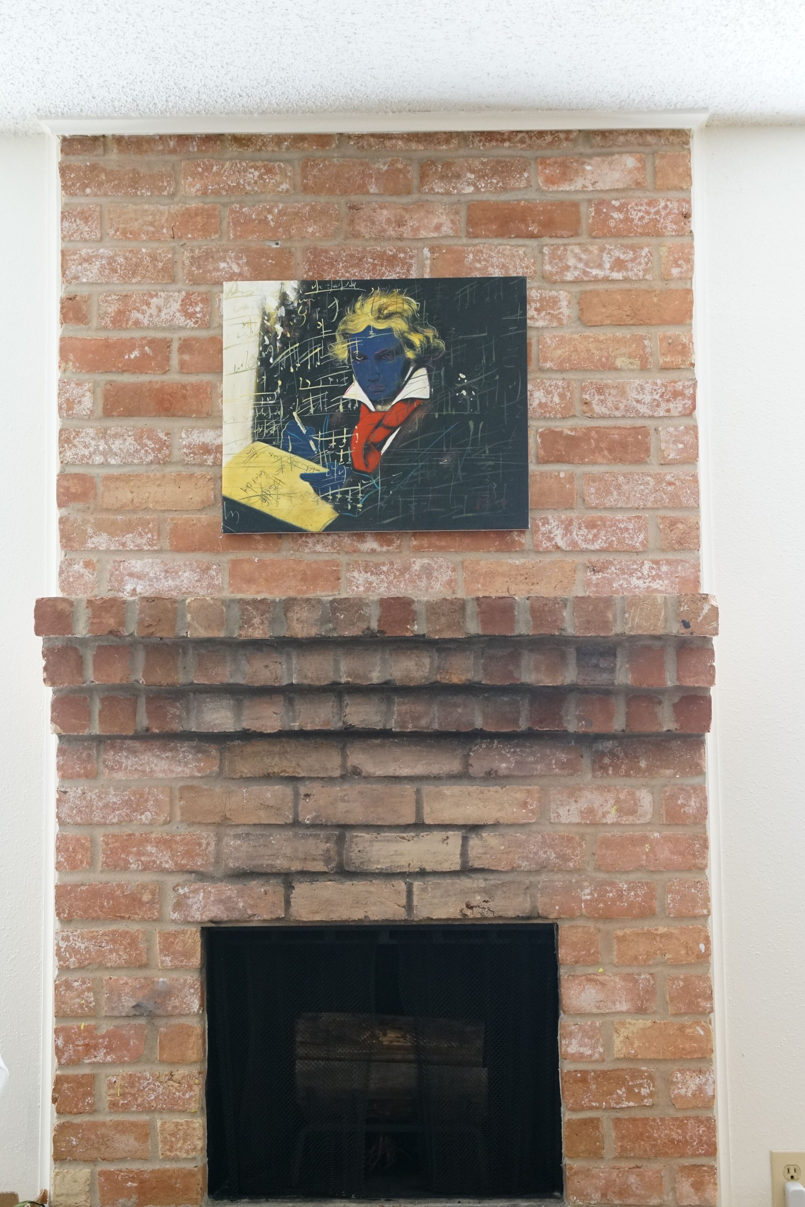 A brick fireplace with a painting above it.