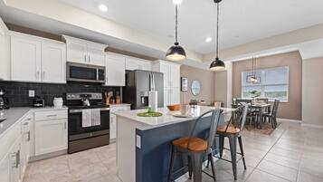 A modern kitchen with white cabinets, stainless steel appliances, and a central island with bar stools.