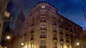 Un edificio histórico de varios pisos, con amplias ventanas y un reloj en la fachada.