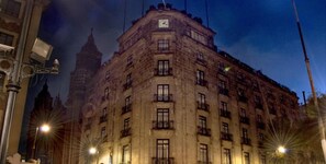 Un edificio histórico de varios pisos, con amplias ventanas y un reloj en la fachada.