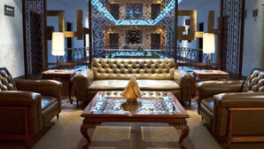 A luxurious living room with a brown leather sofa, a glass coffee table, and two lamps. - Hotel Gillow (Mexico City)