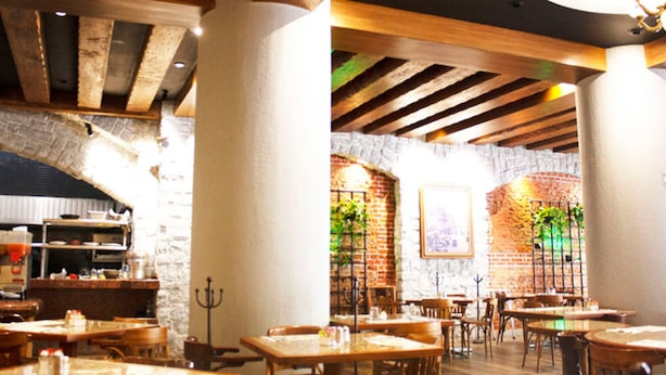 A restaurant interior with exposed wooden beams, stone walls, and brick accents. Tables and chairs are arranged for dining. - Hotel Gillow (Mexico City)