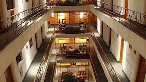 A multi-level atrium with a central open space, railings, and a staircase. - Hotel Gillow (Mexico City)