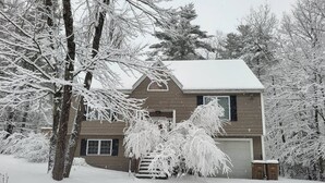 Ein zweistöckiges Haus mit schneebedecktem Dach und Garage.