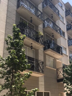 Un edificio a più piani con balconi, finestre e un albero di fronte.