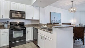 A modern kitchen with white cabinets, a black stove, a microwave, and a granite countertop. - Inspiring view, relaxing ambience, family favorite (Destin)