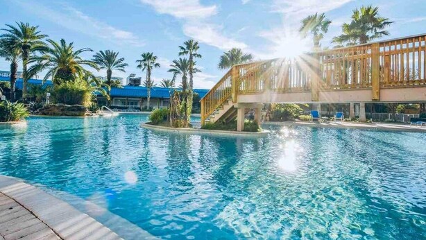 A swimming pool with a wooden deck and palm trees. - Inspiring view, relaxing ambience, family favorite (Destin)