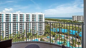 A balcony with a view of a resort pool, palm trees, and a beach. - Inspiring view, relaxing ambience, family favorite (Destin)