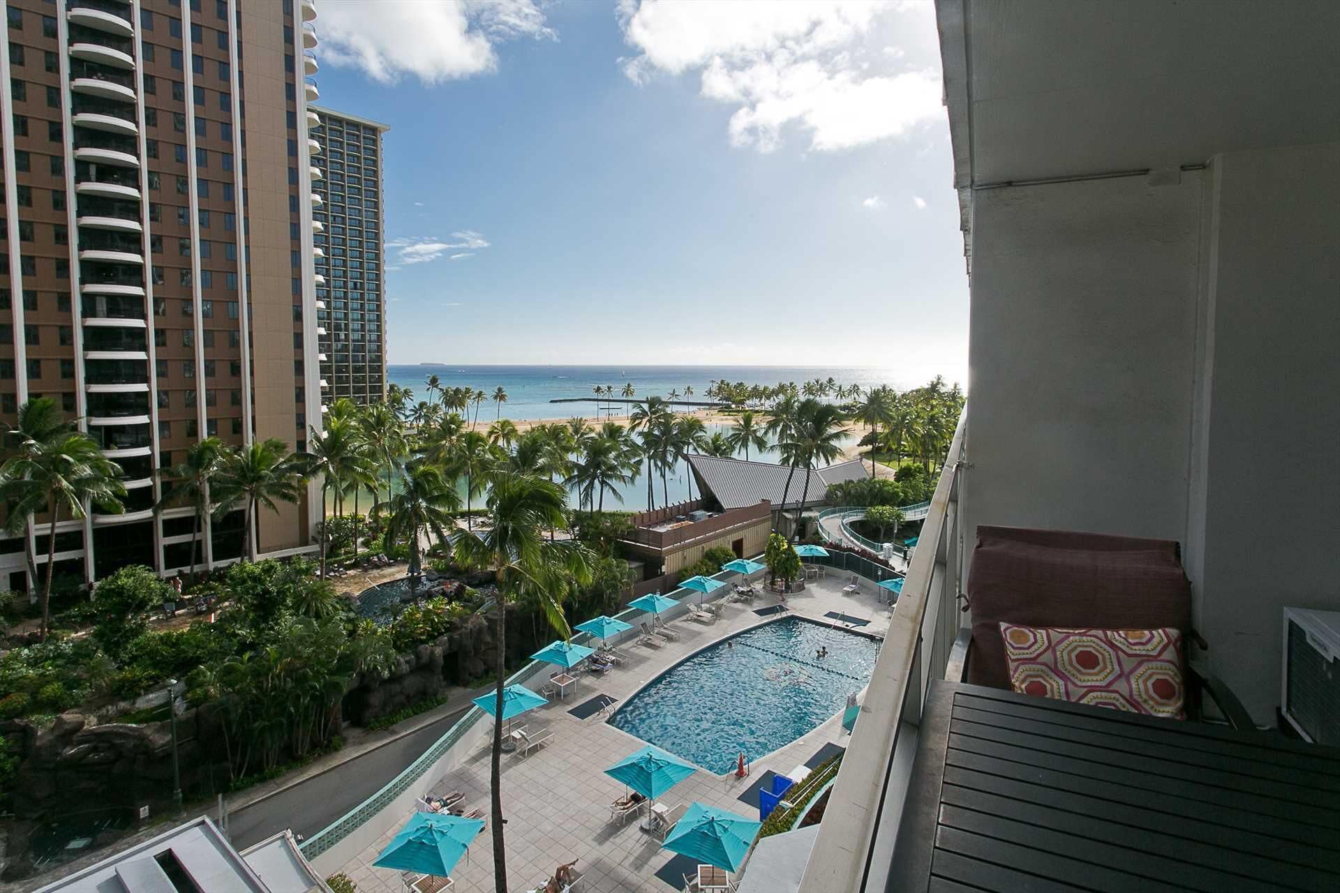 Ein Hotelbalkon mit Blick auf den Strand, einen Swimmingpool und Palmen.