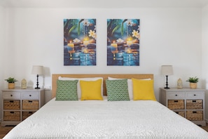 A bedroom with a bed, two nightstands, and a wall-mounted painting.