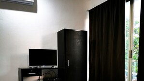 A hotel room with a bed, a television on a desk, a wardrobe, and an air conditioning unit. - Ocean Front Boutique (Playa del Carmen)