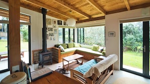 Interior acogedor de una cabaña con techo de madera, un sofá, una mesa y una chimenea.