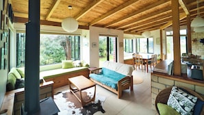 Amplia sala de estar con techo de madera, un sofá, una mesa de comedor y una chimenea.