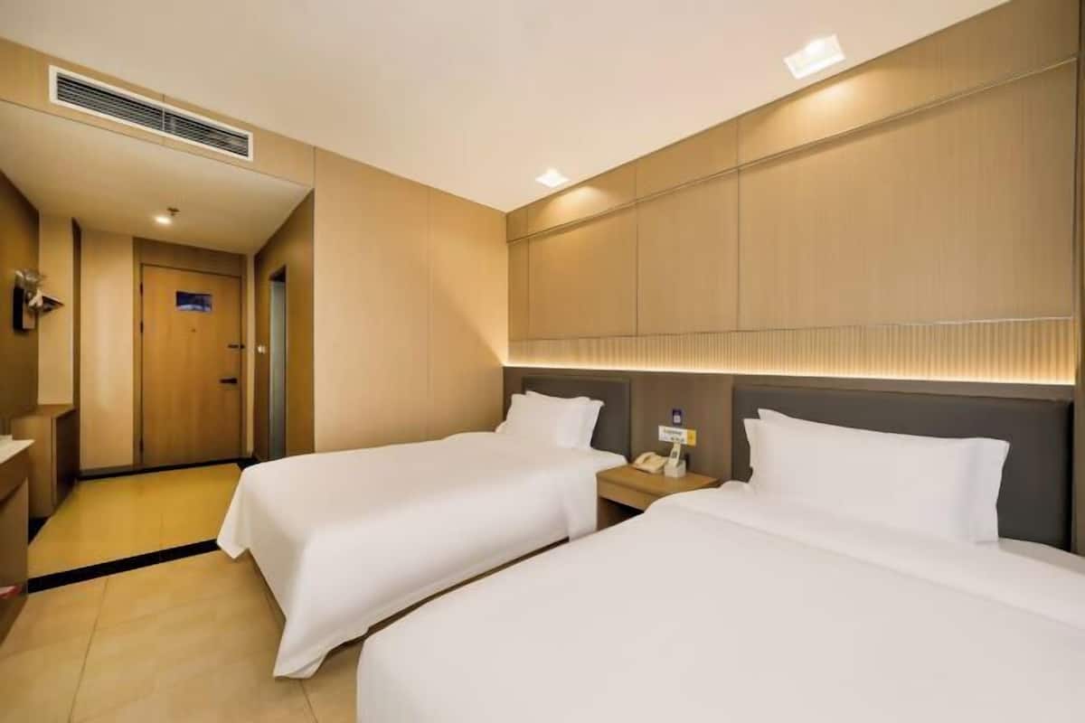 Ein Hotelzimmer mit zwei Betten, einem Schreibtisch, einem Stuhl und einer Tür.
