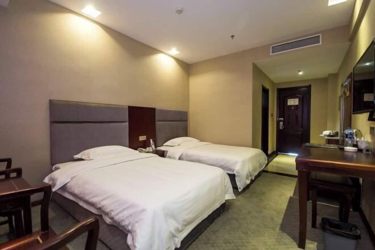 Ein Hotelzimmer mit zwei Betten, einem Schreibtisch und einem Stuhl.