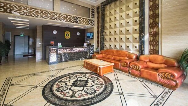 A lobby with a reception desk, a leather sofa, a coffee table, and a patterned rug.