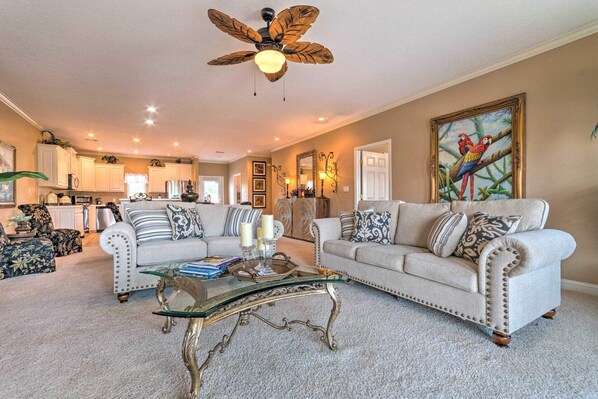 A spacious living room with a high ceiling fan, a dining area, and a kitchen.