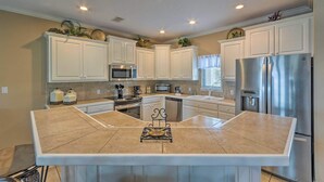 A modern kitchen with white cabinetry, a central island, stainless steel appliances, and recessed ceiling lighting. - Lakeview Condo w/ Balcony+Pool Access, Sunrise View! (Lake Hamilton)