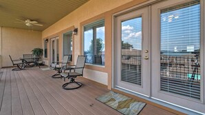 A covered patio with a table and chairs, large windows with blinds, and a ceiling fan. - Lakeview Condo w/ Balcony+Pool Access, Sunrise View! (Lake Hamilton)